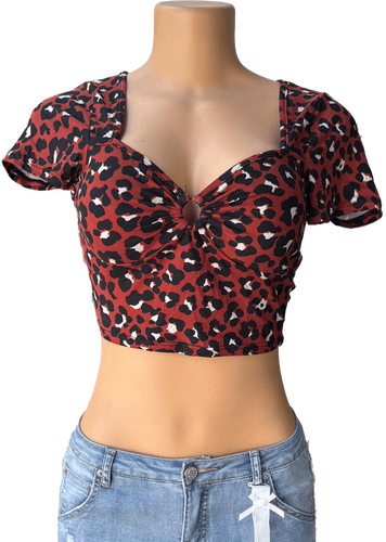 Vista de frente. Blusa corta con estampado de leopardo marrón y detalle anudado al frente.