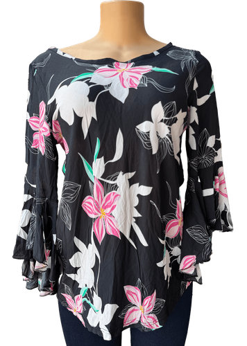 Vista de frente (una de dos). Una blusa negra de manga larga con un estampado de flores en tonos blancos, rosas y verdes.