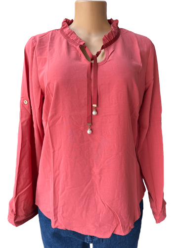 Vista de frente (una de dos). Una blusa roja de manga larga con cuello fruncido y detalle de lazo con perlas.