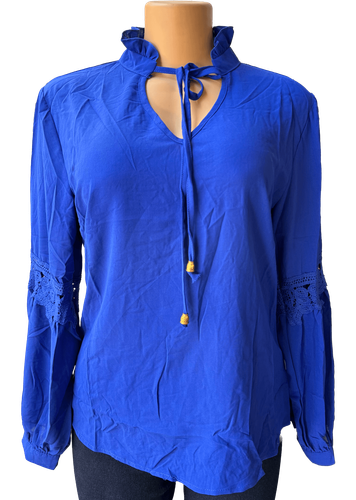 Vista de frente (dos de dos). Una blusa de manga larga azul con detalles de encaje en las mangas y cuello alto.