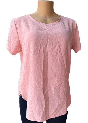 Vista de frente (dos de dos). Blusa simple de color rosa con detalle decorativo en la espalda.