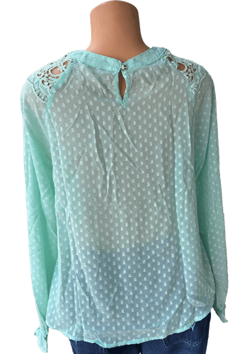 Vista de espalda (una de dos). Blusa transparente verde de manga larga con detalles de encaje en los hombros.