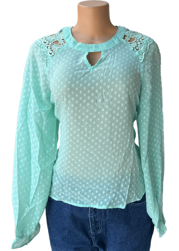 Vista de frente (una de dos). Blusa transparente verde de manga larga con cuello redondo y encaje en los hombros.